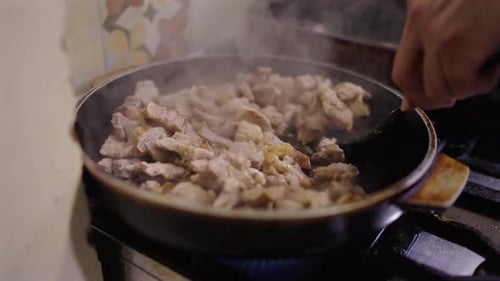 Rustic close-up of pork cooking on gas stove for classic Bagna Cauda preparation