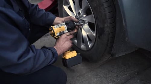 Mechanic Changing Tire with a Powered Wrench