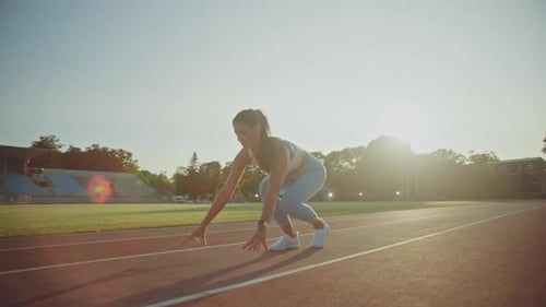 Beautiful Fitness Woman in Light Blue Athletic Top and Leggings is Starting a Sprint Run in an Outd