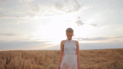 Woman Walking in Wheat Field at Sunset