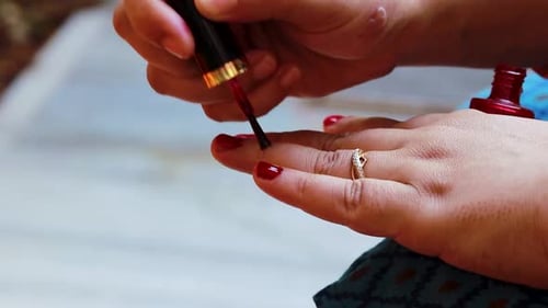 Hands Applying Bright Red Nail Polish