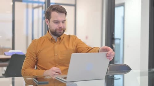 Mann verlässt das Büro, nachdem er den Laptop geschlossen hat