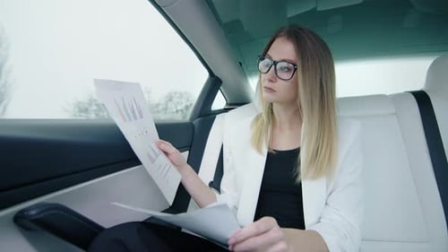 Businesswoman Preparing for a Financial Countdown in the Back Seat of a Car