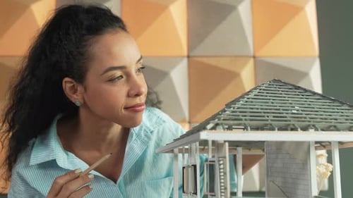 Un ingénieur tient un modèle de maison pendant qu'il inspecte la construction du bâtiment. Manipulateur.