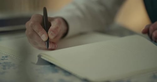 Closeup of Hand Writing Notes in an Open Notebook