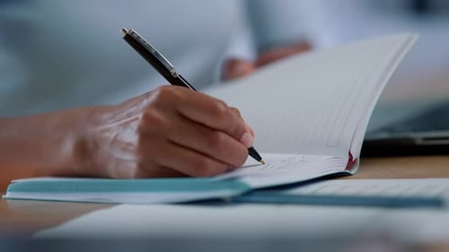 Hand Writes in Notebook with Pen Indoors