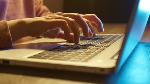 Hands typing on a laptop keyboard, close-up.