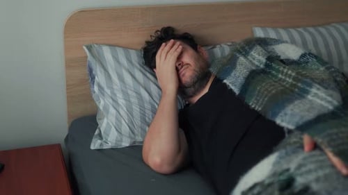 Homme fatigué se couvrant d'une couverture tout en résistant au début de la matinée