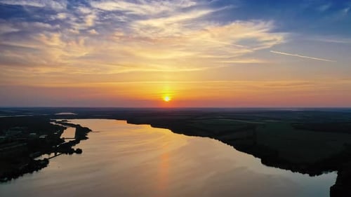 Beautiful river background among fields at dusk. Natural summer landscape in the evening.