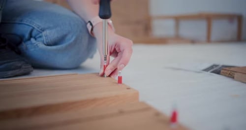 Repairwoman Fitting Screws on Wooden Plank