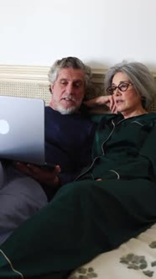 Senior Couple Relaxing in Bed with Laptop
