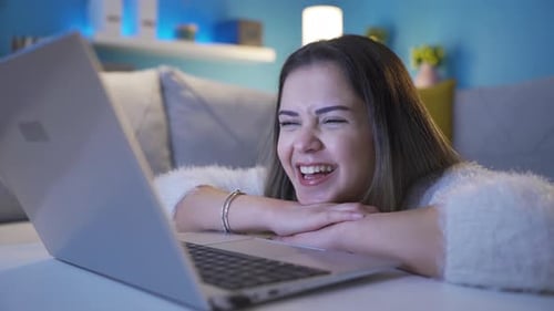 Woman Laughing and Relaxing with Laptop at Home
