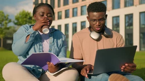 Deux amis, étudiants afro-américains, apprennent à étudier ensemble dans un parc en riant et en parlant
