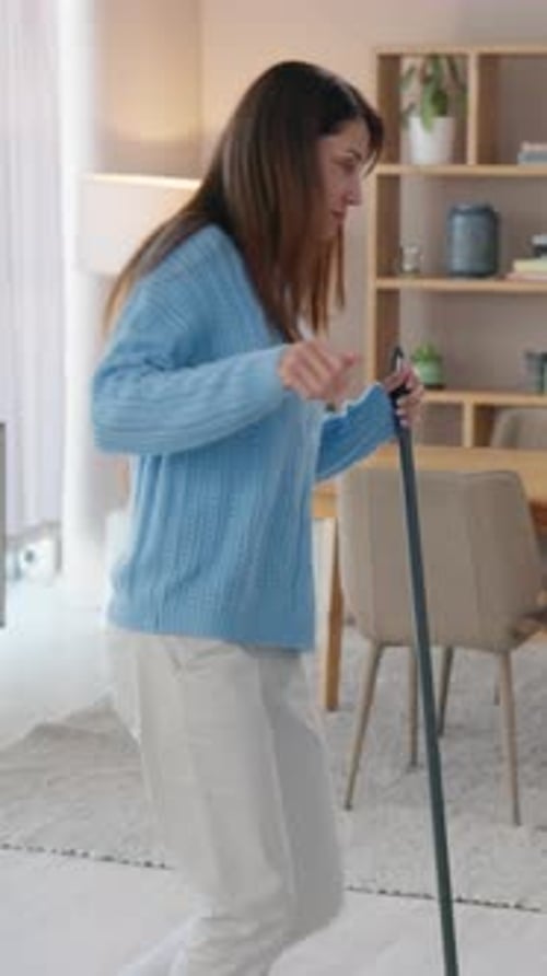 Woman Cheerfully Dancing While Mopping Floor in Home