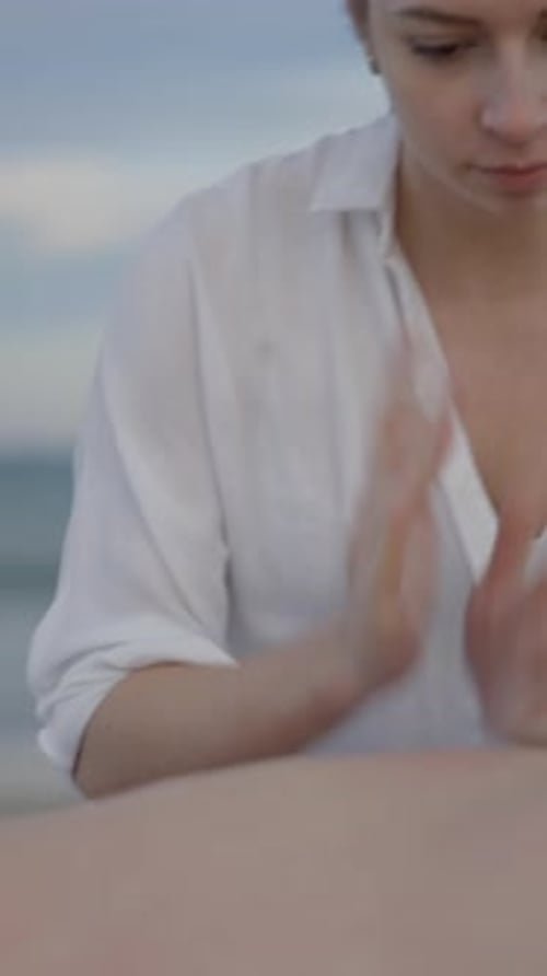 Unrecognizable Man Gets Back Massage with Oil at the Beach Young Caucasian Woman with Strong Hands