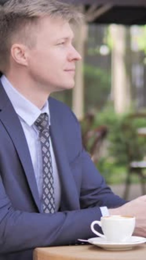 Businessman Celebrating Success on Phone, Sitting in Outdoor Cafe, Vertical Video