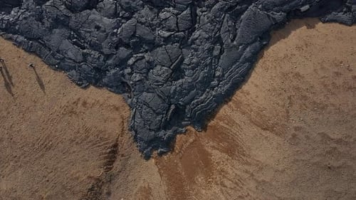 Edge of black basalt lava field with cracked surface rock, Iceland
