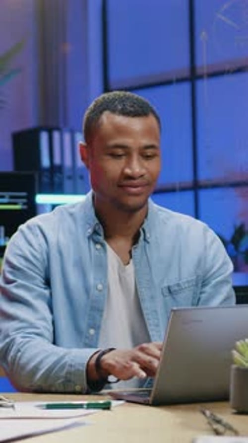 Smiling African American Man Worker Typing on Computer in Modern Office in the Evening