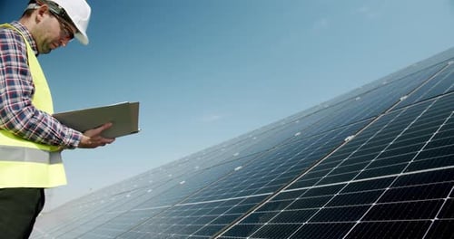 Male Engineer Inspecting Solar Panels