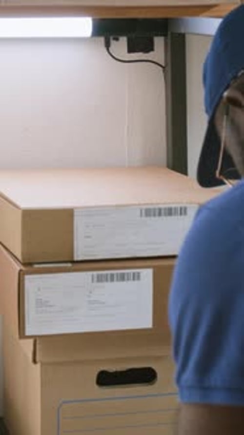 Vertical of Black Male Logistics Depot Operator with Tablet Scanning Packages