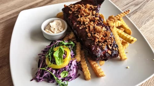 Juicy Steak with Sauce, Fries, and Salad Served in a Restaurant