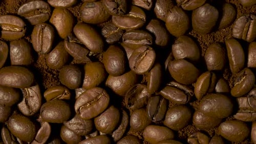 Geröstete Kaffeebohnen, die sich in Zeitlupe drehen. Frisch gebratene Kaffeebohnen rösten
.