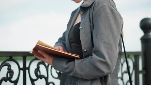 CloseUp View of Lady Holding Open Book Outdoors