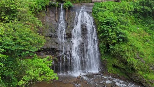 Belle cascade tropicale descendant en cascade d'une falaise rocheuse pour se jeter dans la rivière