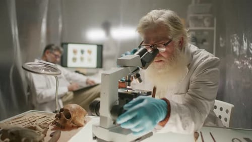 Scientist Examining Skull Under Microscope in Laboratory