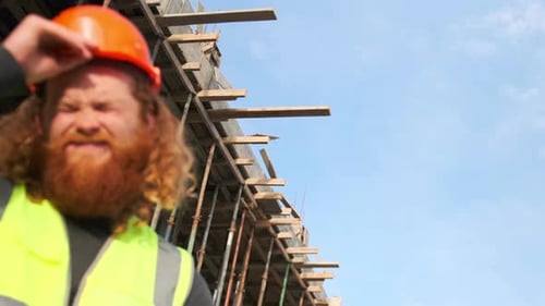 Construction site worker during break rests outdoors, near an unfinished building