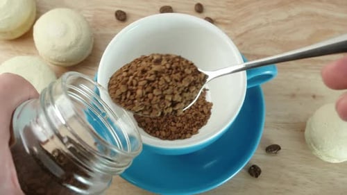Scooping Instant Coffee into White Ceramic Mug
