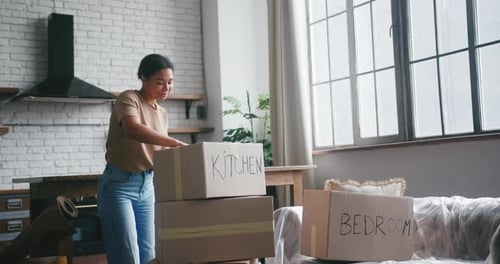 Hispanic Woman Prepares Cardboard Boxes for Moving in Flat