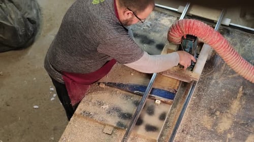 Carpenter Feeds Wood Through a Table Saw Hands Guiding with Expertise The Scene Underscores the