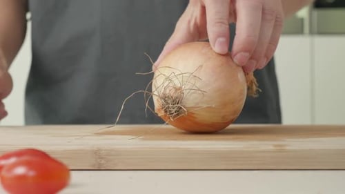 Person Prepares Onion on Cutting Board