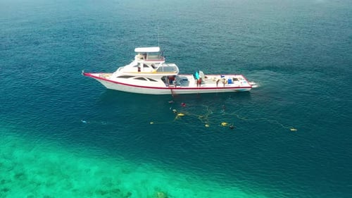 Fishermen on a White Boat Take Out Fishing Nets with Caught Fish Near a Local Island in the Maldives