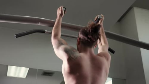 Young caucasian man making pull up with training workout in fitness gym, man hanging with strength.
