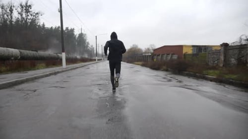 Strong Athlete in Sportswear Jogging Along Trail at Cloudy Day Young Sportsman Running Along Asphalt
