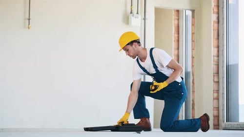 Young construction worker using tools in the unfinished building