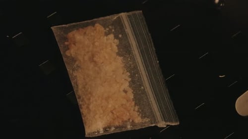 Transparent bag full of MDMA on a black table. Police right bars on.