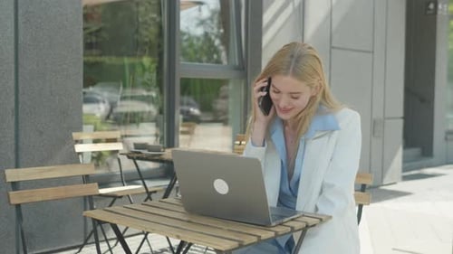 Blonde woman using laptop and smartphone outdoors