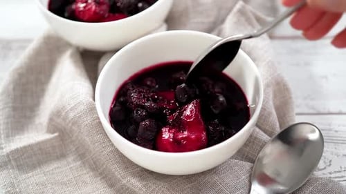 Compote de petits fruits faite maison dans de petits bols blancs sur une table en bois