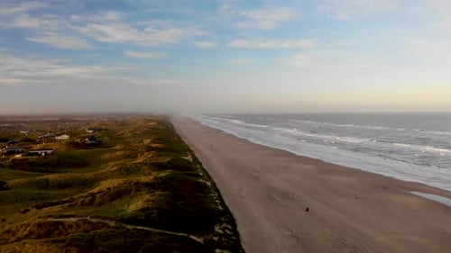 Luftaufnahme des Strandes, des Ozeans und der Sommerhäuser in der Nähe von Løkken an der Nordsee bei Sonnenaufgang