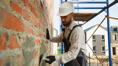 Construction Worker Smoothing Mortar on Brick Wall Outside