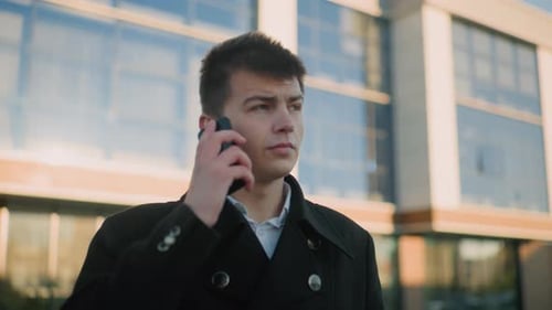 Business Tycoon Taking Call in Urban Setting with Glass Building Backdrop