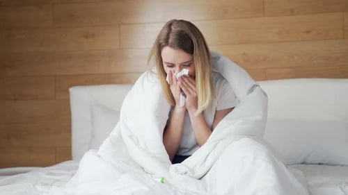 Young Woman with Cold Sitting in Bed