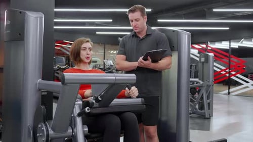 Woman Works Out with Personal Trainer at Gym