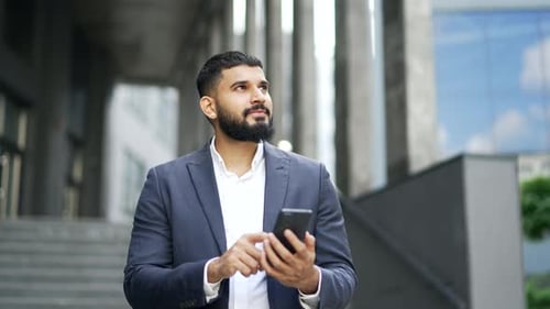 Smiling Young Adult Using Smartphone Outside Office Building