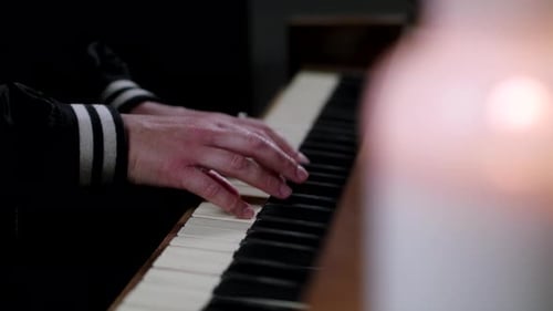 Una mujer tocando el piano cerca de la luz de las velas.