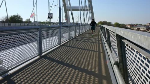 Male runner running on the bridge in the city during day.