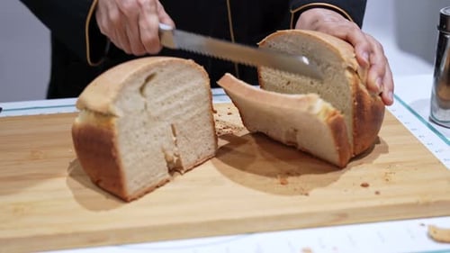 Fresh Homemade Bread Loaf Being Sliced with Knife on Wooden Cutting Board
